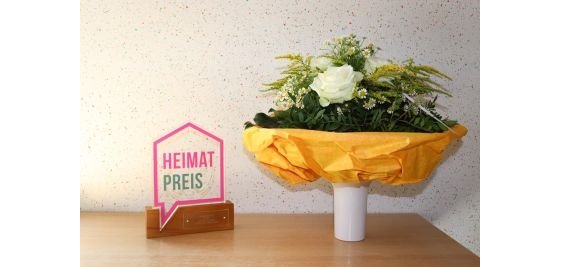 Blumenstrauß und Heimatpreis Auszeichnung auf Sockel Blumenstrauß und Heimatpreis Auszeichnung auf Sockel