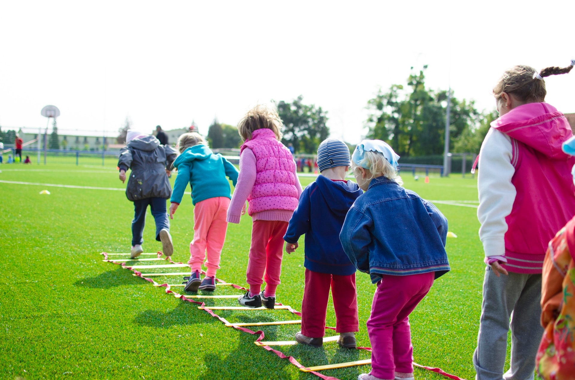 Kinder Springen über eine auf dem Boden liegende Leiter
