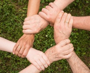 Mehere Personen greifen sich an den Handgelenken, sodass dies einen Kreis formt