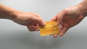 Eine Person übergibt einer anderen eine goldene Ehrenamtskarte Eine Person übergibt einer anderen eine goldene Ehrenamtskarte